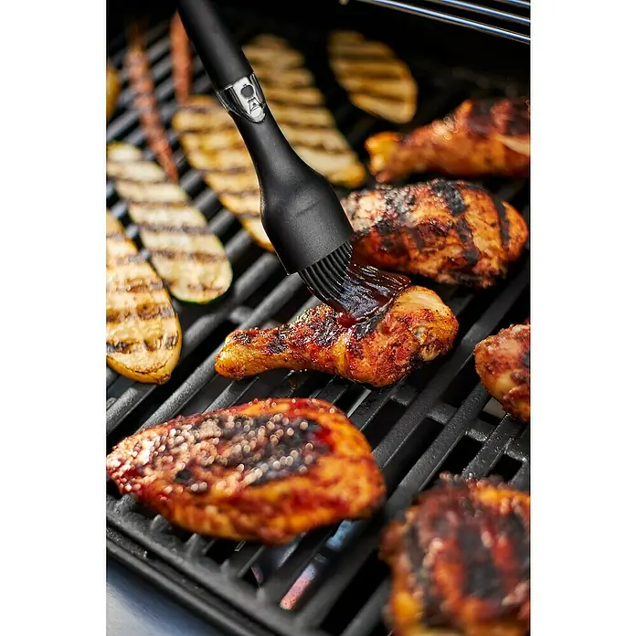 Weber Barbacoa de gas Spirit E-215 GBS - Superficie de la parrilla (An x Pr): 52 x 45 cm, Número de quemadores: 2 - Muslo de pollo marinado que se está rociando en la parrilla con una brocha, junto con calabacín y pechugas de pollo a la parrilla.