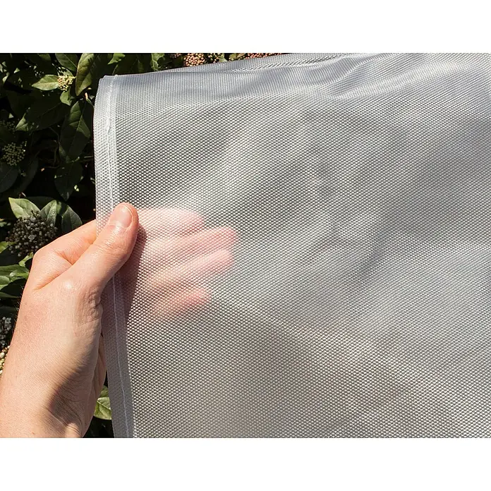 Campingaz Funda protectora para mesa de jardín L ovalada rectangular - L x An x Al: 240 x 165 x 90 cm - Primer plano de una malla sostenida por una mano, destacando la malla fina y la transparencia del tejido.