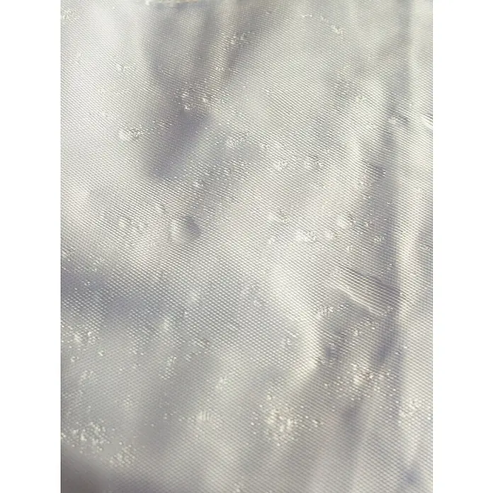 Campingaz Funda protectora para mesa de jardín L ovalada rectangular - L x An x Al: 240 x 165 x 90 cm - Primer plano de un tejido blanco con una textura fina y efectos de luz sutiles, acentuando la suavidad del material.