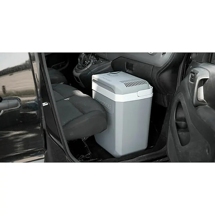 Campingaz Nevera de camping Powerbox Plus - 28 l, 31 x 41 x 47 cm - Una nevera gris Campingaz se ubica en el espacio para los pies de un coche, proporcionando una solución de refrigeración práctica para uso en movimiento.