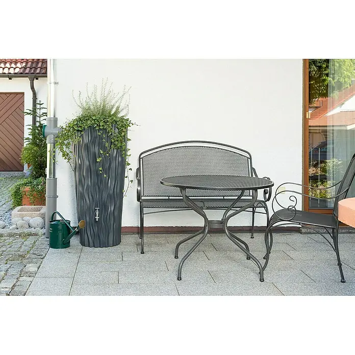 Arves Regenspeicher Alana - 160 l, Anthrazit - Eine Regentonne im wellenförmigen Design steht neben einem Gartentisch und einer Bank auf einer Terrasse.