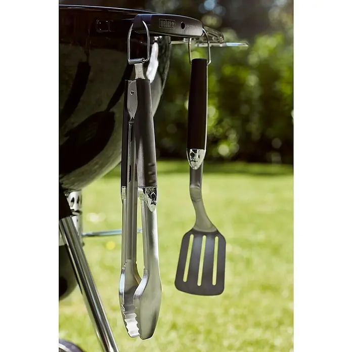 Weber Master-Touch GBS Barbacoa redonda con tapa GBS E-5750 - Diámetro de la superficie de la parrilla: 57 cm, Negro - Pinzas y espátula para parrilla colgando de una parrilla Weber, listas para usar en la próxima barbacoa. Accesorios prácticos para todo maestro de la parrilla.