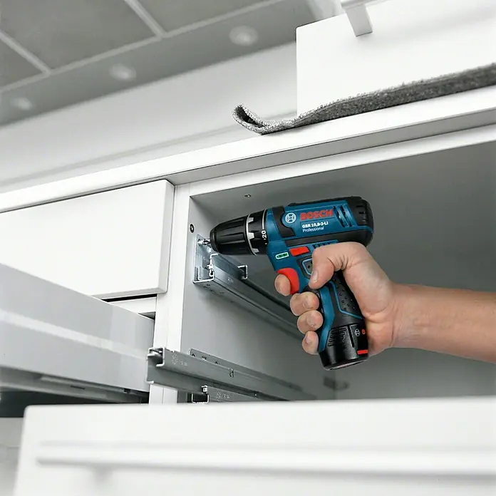 Bosch Professional Akku-Schlagbohrschrauber GSB 12V-15 L-Boxx - 12 V, Ohne Akku, 0 Ah, 30 Nm, Ohne Akku mit Holster - Ein blauer Bosch GSR 10,8-2-LI Professional Akku-Bohrschrauber wird verwendet, um eine Schraube in einen weißen Schrank einzudrehen.