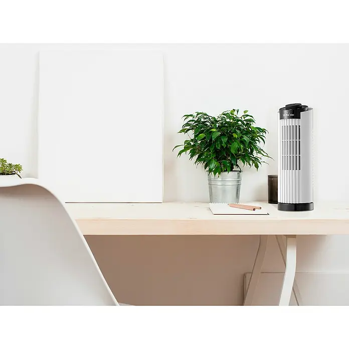 Purline Venty Ventilador de torre TO 10 - Blanco, 33 cm - Un elegante ventilador de torre blanco con un panel de control negro está sentado en un escritorio luminoso al lado de una planta en maceta.