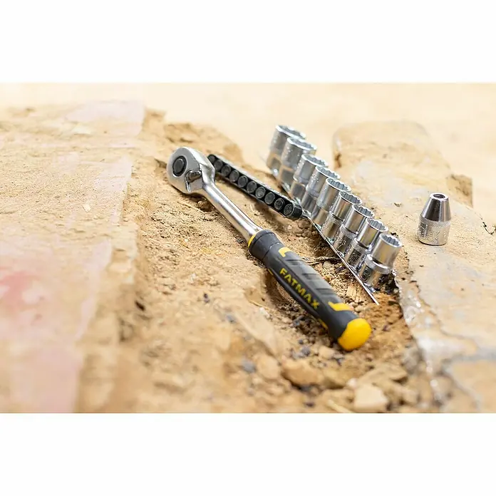 Stanley FatMax Set de llaves de vaso FMMT82680-0 - 22 pzs., Tamaño de accionamiento: ⅜″ - Una llave de carraca Fatmax y un juego de vasos se asientan sobre una superficie irregular.