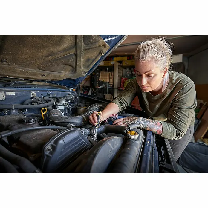 Stanley FatMax Set de llaves de vaso FMMT82680-0 - 22 pzs., Tamaño de accionamiento: ⅜″ - Una mujer rubia con tatuajes repara un motor de coche azul con el capó abierto, usando una llave.
