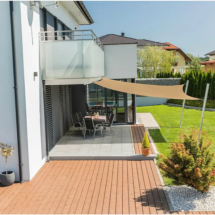 Windhager Sonnensegel Capri - L x B: 4 x 4 m, Quadratisch, Schilf - Blick auf eine Terrasse mit einem beigefarbenen Sonnensegel, das Schatten spendet. Tisch und Stühle stehen einladend bereit.