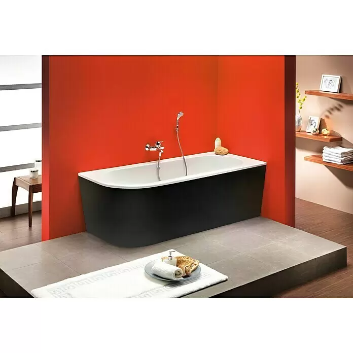 Ottofond Badewanne Siesta Corner - 178 x 78 cm, Sanitäracryl, Schwarz/Weiß, Links - Moderne schwarz-weiße Badewanne mit Chromarmaturen in einem Badezimmer mit orangefarbenen Wänden und grauem Fliesenboden.