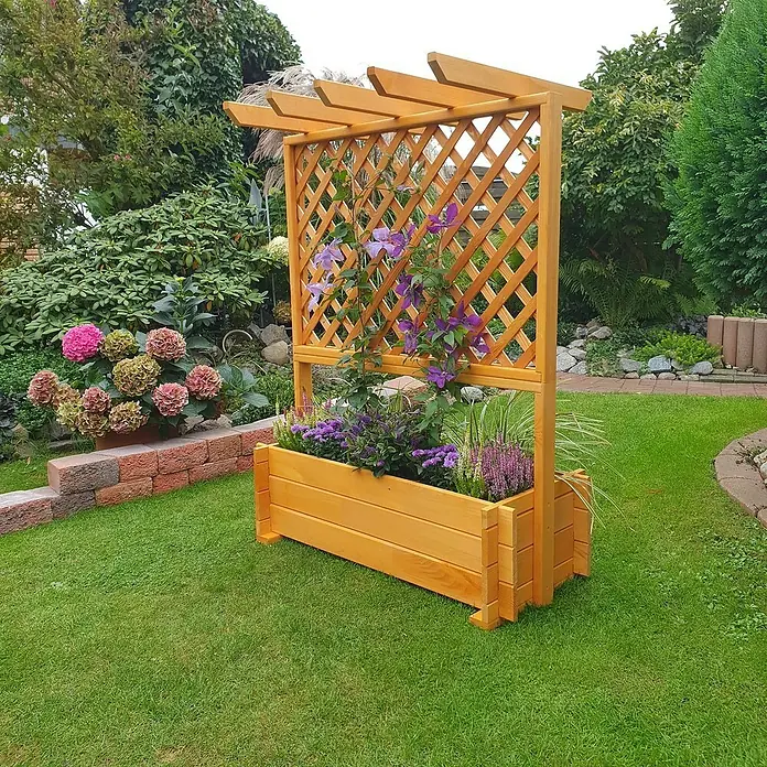 Promadino Pflanzkasten mit Pergola - Außenmaß (L x B x H): 112 x 65 x 139 cm, Holz, Honigbraun - Eine hölzerne Pflanzkasten-Kletterhilfe mit lila Blumen und einem gitterartigen Rankgitter, umgeben von üppigem Grün.