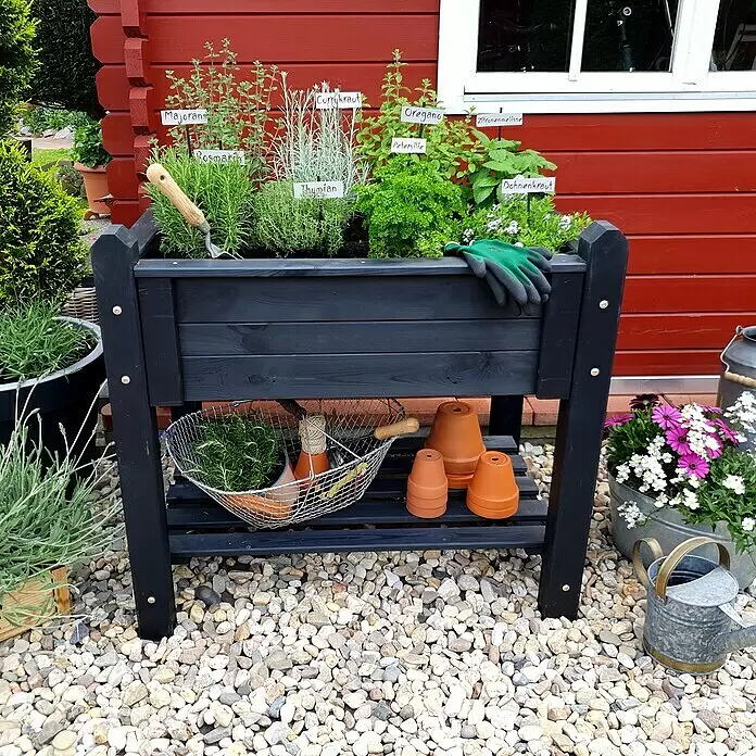 Promadino Kräuterhochbeet - L x B x H: 90 x 60 x 84,5 cm, Anthrazit - Schwarzes Holz-Hochbeet für Kräuter, gefüllt mit Pflanzen, Gartengeräten und Terrakotta-Töpfen auf der unteren Ablage.