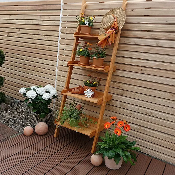 Promadino Blumentreppe Helma - 58 x 46 x 177 cm, Kiefer, Braun - Eine hölzerne Leiterregal mit Blumentöpfen, einem Hut und dekorativen Kugeln, die eine charmante Gartenszene erzeugen.\n