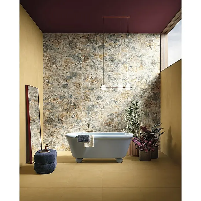 Feinsteinzeugfliese Mediterran Sun Gold - 120 x 120 cm, Ocker, Matt - Elegantes Badezimmer mit blumigen Fliesen und freistehender Badewanne, akzentuiert durch eine moderne Hängeleuchte.