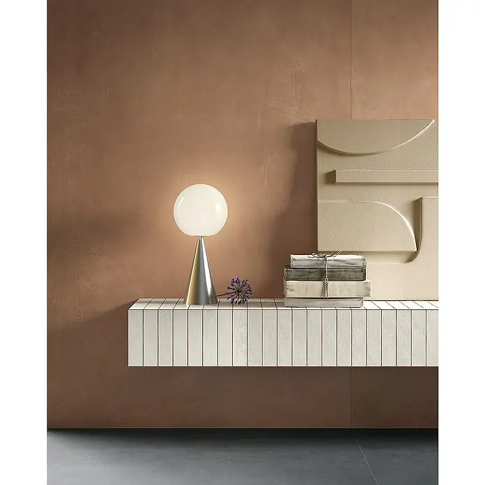 Feinsteinzeugfliese Mediterran Canyon - 120 x 120 cm, Cotto, Matt - Elegantes Interieur mit einer stilvollen Lampe, Büchern und einem einzigartigen Dekostück auf einer modernen Kommode.
