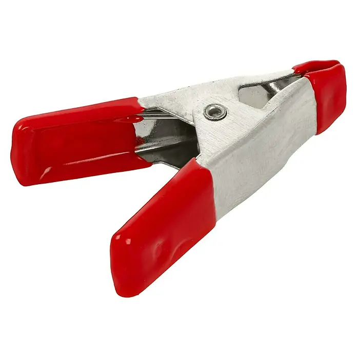 Alpha Tools Zwingen-Set - Spannweite: 20 mm, Ausladung: 20 mm - Nahaufnahme einer Federklemme mit roten Griffen und silberfarbenen Metallkörper, die zum Fixieren und Halten von Gegenständen verwendet wird.
