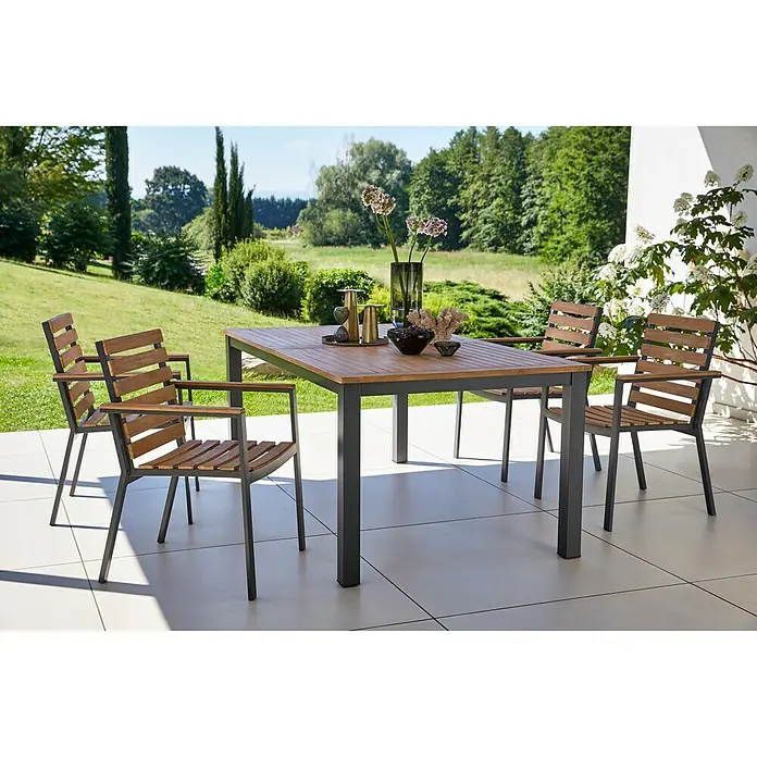 Gartenmöbel-Set Carina - 5 -tlg., Akazie/Stahl, Naturbraun/Grau - Outdoor-Esstisch mit vier passenden Stühlen auf einer Terrasse mit Blick auf einen Garten.