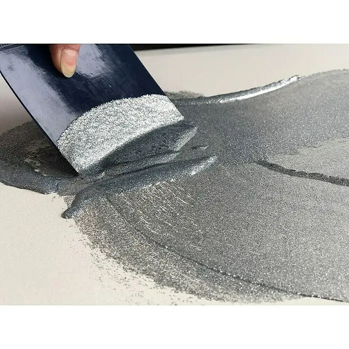 Fleur Purpurina Glitter - Plateado, 90 g, Brillante - Primer plano de una espátula aplicando pintura de purpurina plateada sobre una superficie blanca, creando un efecto brillante.