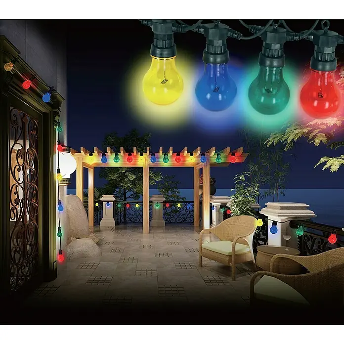 Globo LED-Lichterkette Nirvana - Außen, Anzahl Leuchtmittel: 10 Stk. - Mehrfarbige Glühbirnen erhellen eine Terrasse mit Korbmöbeln und einer Pergola, die eine warme und einladende Atmosphäre schaffen.