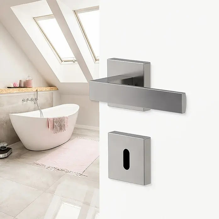 Diamond Doors Creative Zimmertürgarnitur Savannah - Stärke Tür: 40 mm - 45 mm, Samtgrau, Buntbart - Nahaufnahme eines modernen, quadratischen Türgriffs aus gebürstetem Stahl mit Schlüsselloch in einem stilvollen Badezimmer.