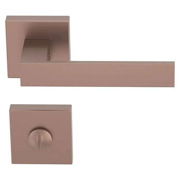 Diamond Doors Creative Zimmertürgarnitur WC Savannah - Stärke Tür: 40 mm - 45 mm, Kupfer, Schlitzkopf/Olive - Nahaufnahme eines modernen, quadratischen Türdrückers und -schilds in einem warmen Roségold-Farbton vor einem neutralen, schwarzen Hintergrund.
