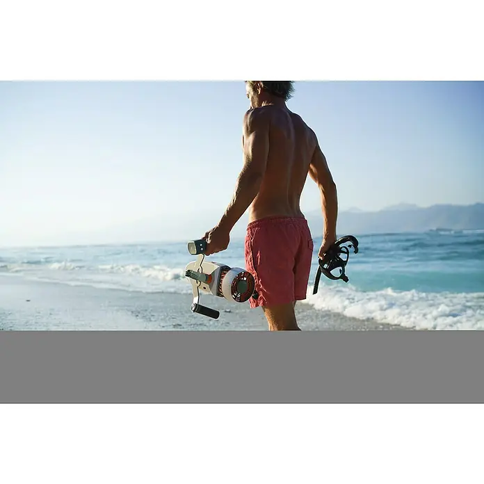 Sublue Tauchscooter Tini - L x B x H: 355 x 135 x 135 mm - Ein Mann am Strand mit einer Geneinnova Unterwasser-Scooter, bereit für ein Abenteuer im Meer.