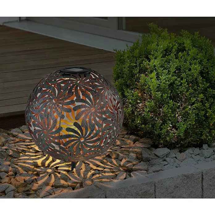 Solar-Dekoleuchte Kugel Blumen - 0,06 W, Gold, IP44 - Dekorative Solarleuchte in Kugelform mit filigranem Blumenmuster, die warmes Licht auf Steine wirft.