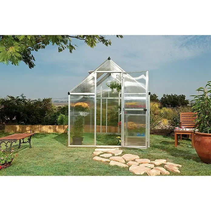 Palram – Canopia Gewächshaus Mythos 6x8 - Außenmaß inkl. Dachüberstand (B x T): 185 x 247 cm, 4 mm, Silber/Transparent - Das Bild zeigt ein Gewächshaus mit geöffneten Türen, umgeben von einem Garten mit Steinen und Pflanzen.