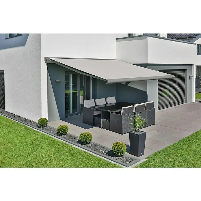 Deyo Limassol Vollkassettenmarkise - Beige Struktur, Farbe Gestell: Weißaluminium Feinstruktur, Breite: 5,5 m, Ausfall: 3,5 m - Eine graue Gelenkarmmarkise spendet Schatten über einem Terrassenbereich mit Esstisch und Stühlen, ideal für entspannte Stunden im Freien.
