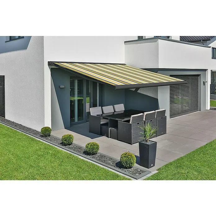 Deyo Limassol Vollkassettenmarkise - Gelb/Grau/Beige, Farbe Gestell: Eisenglimmer matt, Breite: 3,5 m, Ausfall: 3 m - Eine gelb-weiß gestreifte Markise spendet Schatten über einem Terrassenbereich mit Gartenmöbeln. Perfekt für entspannte Stunden im Freien.