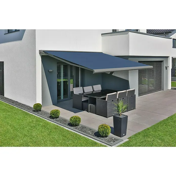 Deyo Limassol Vollkassettenmarkise - Blau, Farbe Gestell: Weißaluminium Feinstruktur, Breite: 5,5 m, Ausfall: 3,5 m - Eine moderne Terrassenüberdachung bietet Schatten für ein Ess-Set aus Rattan auf einer gepflasterten Terrasse neben einem Rasen.