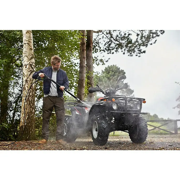 Nilfisk Hidrolimpiadora de alta presión Premium 200-15 - 200 bar, 3.300 W, Capacidad de bombeo: 650 l/h - Un hombre lava a presión un ATV negro en un entorno verde al aire libre.