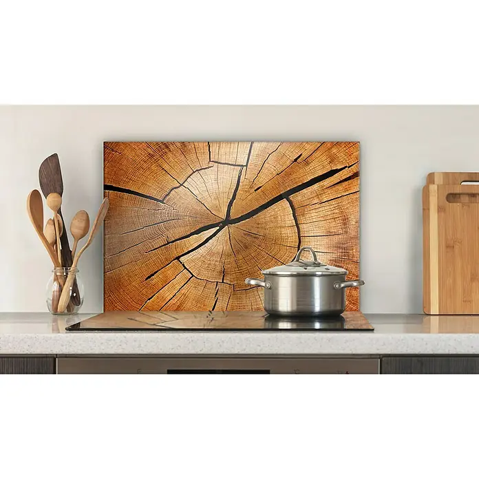 CUCINE Küchenrückwand - Circled Wood, 60 x 40 cm, Stärke: 6 mm, Einscheibensicherheitsglas (ESG) - Das Bild zeigt eine Glasabdeckplatte mit einem Baumscheibenmuster, auf der ein Kochtopf auf einem Herd steht, zusammen mit Kochutensilien und Schneidebrettern.