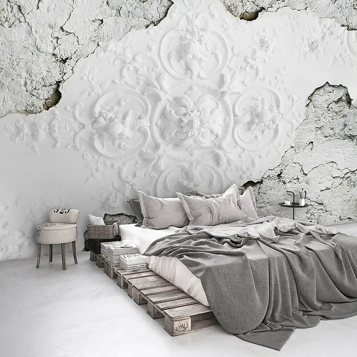Fototapete FlachreliefB x H: 312 x 219 cm, Vlies - Ein gemütliches Schlafzimmer mit einem Bett auf Paletten, grauer Bettwäsche und einer kunstvollen Wand im Hintergrund.