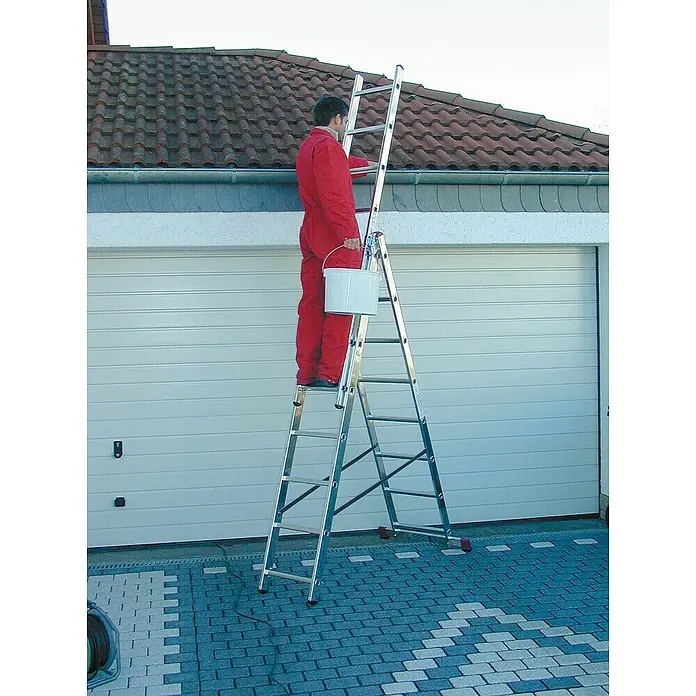 Krause Corda Mehrzweckleiter - Anzahl Tritte: 24 Stk., Arbeitshöhe: 5,4 m, Belastbarkeit: 150 kg, Aluminium, Treppengängig - Mann auf einer Mehrzweckleiter vor einer Garage. Die Leiter ist aus Aluminium gefertigt und steht auf einem gepflasterten Untergrund.