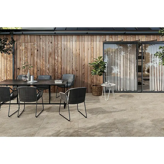 Atlas Concorde Solution Regent Terrassenfliese Ivory - 45 x 90 x 2 cm, Beige/Braun, Matt - Einladende Außenansicht mit Natursteinpflaster, Esstischgruppe und großzügigen Glasschiebetüren, die den Übergang zum Innenraum ermöglichen.