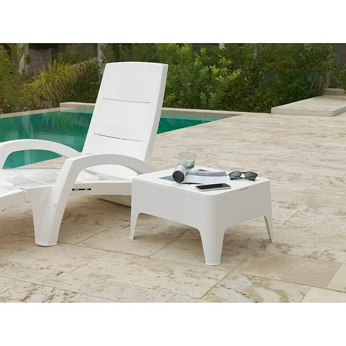Mesa auxiliar de jardín Alaska - L x An x Al: 58 x 48 x 30 cm, Polipropileno, Blanco - Imagen de una tumbona de jardín blanca y una mesa auxiliar junto a la piscina con bebida, teléfono, gafas de sol y revista.
