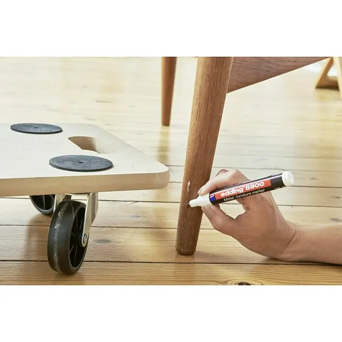 Edding Marcador permanente para muebles - Grosor de trazo: 1,5 mm - 2 mm, Roble claro - Se utiliza un rotulador de reparación de muebles para retocar los arañazos de una pata de silla de madera. Un carro para muebles está al lado.