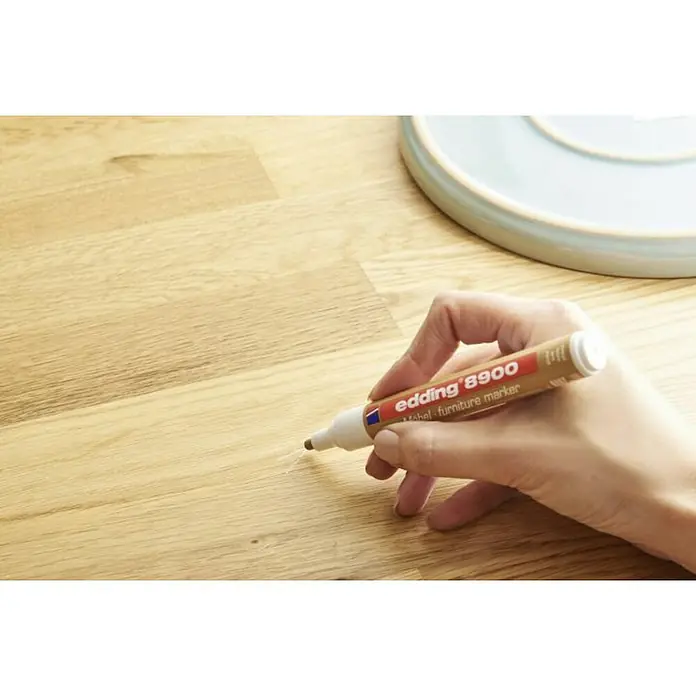 Edding Marcador permanente para muebles - Grosor de trazo: 1,5 mm - 2 mm, Roble claro - Una mano sujetando un rotulador para muebles Edding 8900 para retocar arañazos en una superficie de madera. Ideal para reparaciones rápidas.