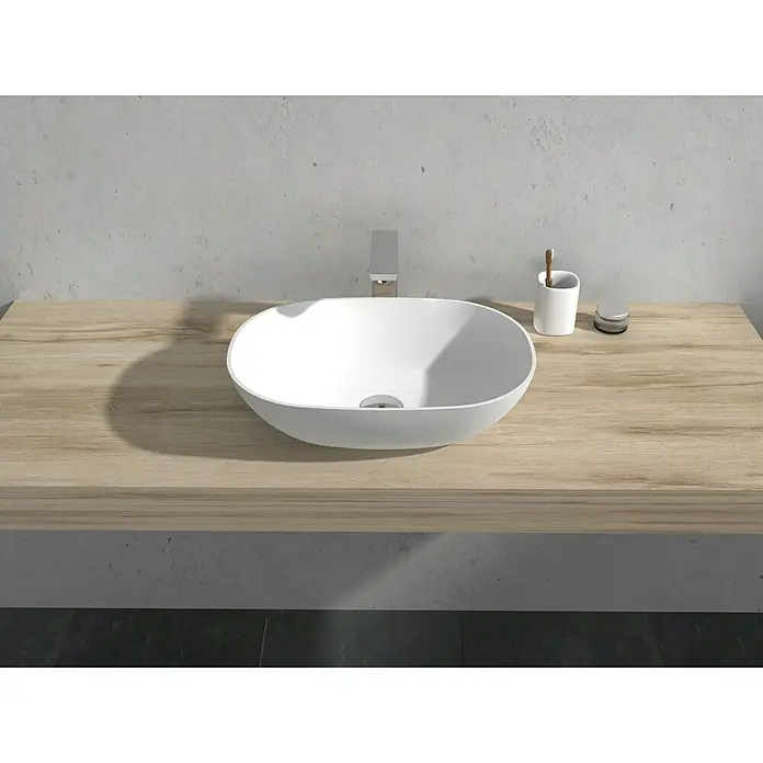 Camargue Lavabo Estanyol - 50 x 35 cm, Con esmalte antibacteriano, Sin desbordamiento, Blanco - Lavabo sobre encimera de cerámica blanca. El lavabo está colocado sobre una encimera de madera con grifo plateado.