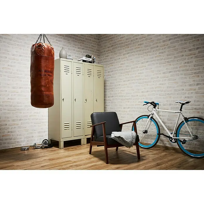A.S. Création New Walls Vliestapete Stein - Pastell, Steinoptik, 10,05 x 0,53 m - Ein Boxsack hängt in einem Raum mit einem Stuhl, einem Fahrrad und Schließfächern.