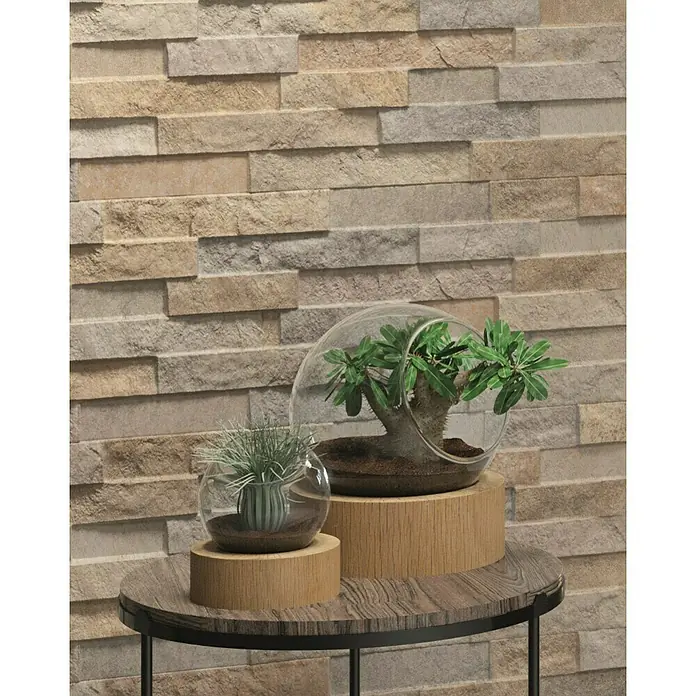 Verblendstein Canyon Mix - 60 x 20 cm, Beige, Steinoptik - Nahaufnahme von zwei Glaspflanzgefäßen mit Pflanzen auf einem kleinen, runden Tisch vor einer Ziegelwand.