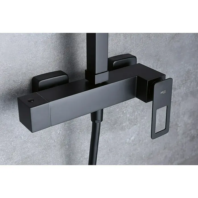 Imex Suecia Sistema de ducha - Con grifo monomando, Negro - Primer plano de un grifo de ducha IMEX negro con un diseño cuadrado sobre una pared gris.