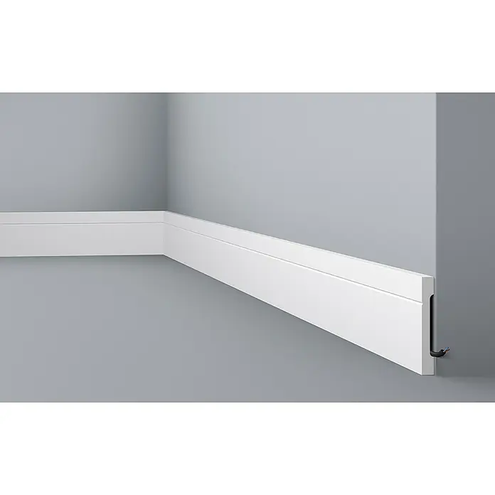 Nmc Decoflair Zierprofil Sockelleiste C12 - 2 m x 1,5 cm x 11 cm, Hochverdichtetes extrudiertes Polymer (HDPS) - Ein nahes Bild einer Fußleiste an einer grauen Wand. Das Kabel ist durch eine versteckte Nut geführt.
