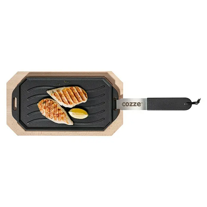 Cozze Grillpfanne - L x B: 30 x 15 cm, Höhe: 1 cm, Gusseisen - Ein Cozze Grill mit gegrilltem Hähnchen und Zitrone, präsentiert auf einem Holzteller mit Griff. Ideal für köstliche Mahlzeiten.