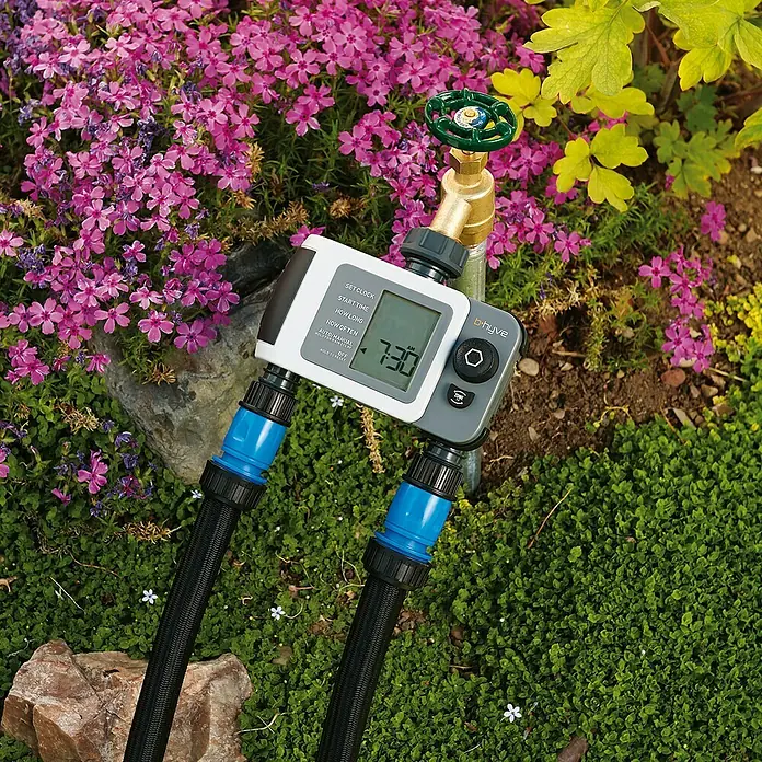 Programador de riego doble XD - ¾″, Específico para: 2 salidas - Un temporizador de riego digital con dos salidas instalado en un jardín floreciente.