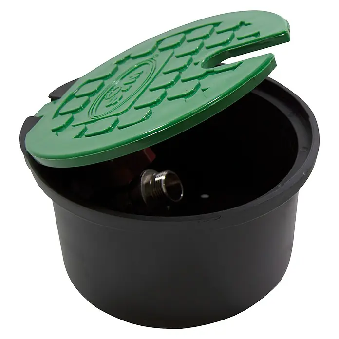 Arqueta redonda con tapa - Dimensión conexión: ¾″ - Caja de válvulas de riego negra con tapa verde, ligeramente abierta, que revela un accesorio de metal en el interior.