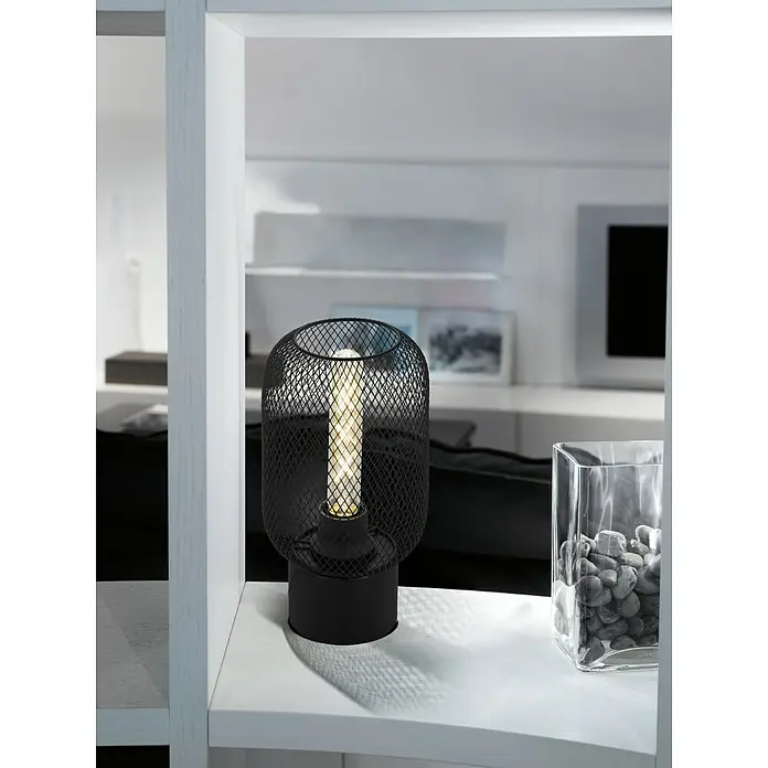 Eglo Wrington Tischleuchte - 60 W, Schwarz, E27 - Eine moderne Tischleuchte mit einem schwarzen Metallgitter-Schirm und einer warmen Glühbirne steht auf einem weißen Regal.