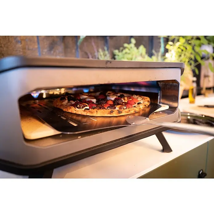 Cozze Horno para pizza gas 17" - 8 kW - Un horno de pizza con una deliciosa pizza cubierta con frutos rojos frescos, que se está preparando sobre una pala de pizza en el interior del horno.
