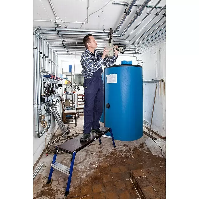 Krause Monto Arbeitsplattform StepTop - Anzahl Tritte: 1 Stk., Arbeitshöhe: 2,45 m, Aluminium - Mann in blauer Arbeitskleidung bedient graues Pressgun 4B Presswerkzeug zur Verbindung von Deckenrohren.