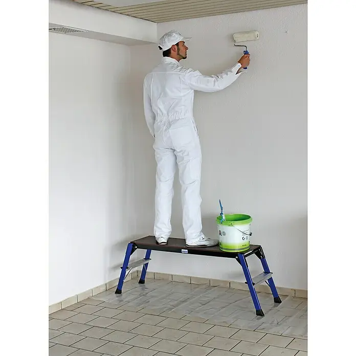 Krause Monto Arbeitsplattform StepTop - Anzahl Tritte: 1 Stk., Arbeitshöhe: 2,45 m, Aluminium - Maler auf einer Klapptritt, streicht eine Wand. Die Klapptritt ist blau und schwarz, und der Maler trägt einen weißen Overall.