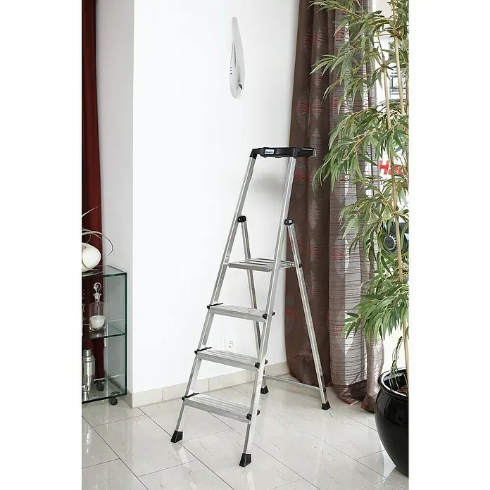 Krause Monto Stehleiter Secury MultiGrip - Anzahl Tritte: 4 Stk., Arbeitshöhe: 2,85 m, Belastbarkeit: 150 kg, Aluminium - Eine silberfarbene Krause-Trittleiter steht vor einer Wand, ideal für Hausarbeiten und kleine Reparaturen.